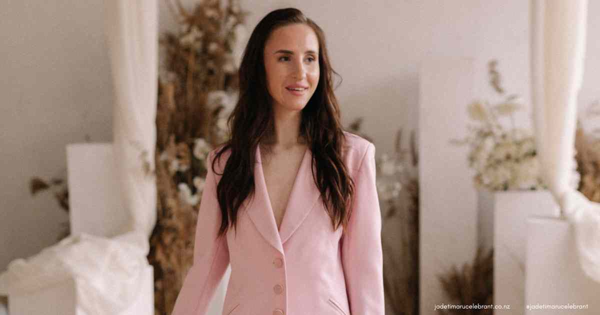Woman with long wavy brown hair wearing a pale pink suit at a wedding venue. Jade Tiamru Wedding Celebrant in Timaru, South Canterbury, New Zealand