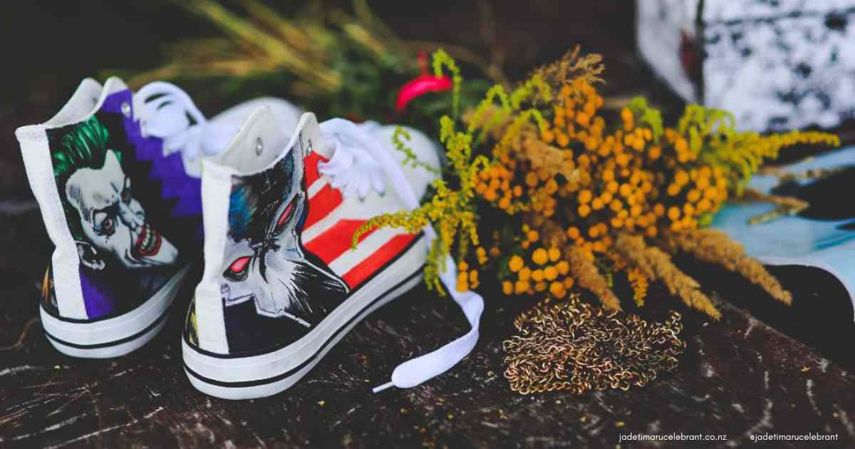 Colourful converse shoes with the joker on them with mustard-coloured dried wedding flowers laying beside them on the ground. Timaru Wedding Celebrant Jade Whaley. 