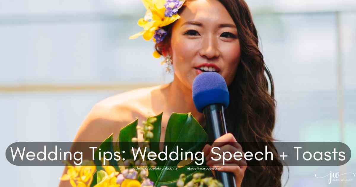 Asian beautiful bridesmaid with yellow flowers and greenery in her long black hair, with a wedding bouquet being shown. She is speaking into a large, blue microphone. Timaru Wedding Celebrant Jade Whaley, NZ.