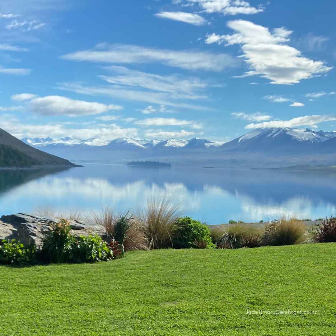 Elopement Wedding Package at the Lupins with the clear waters of Lake Tekapo, New Zealand, reflect the Southern Alps snow-capped mountains and blue sky. 